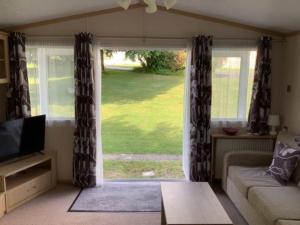 a living room with a couch and a large window at Beautiful 6 Berth Caravan With Wifi In Hampshire Ref 81337sb in Milford on Sea