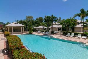 a large swimming pool with chairs and palm trees at Lahania by the Sea - JJ Place in Clifton Beach