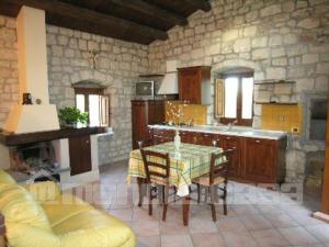 eine Küche mit einem Tisch und einer Steinmauer in der Unterkunft Le case di don Peppino in Pietre Nere San Zagaria