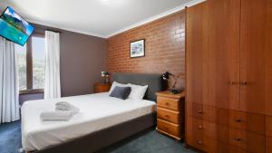 a bedroom with a bed and a brick wall at Lindsay Lachen in Mount Hotham +7 photos