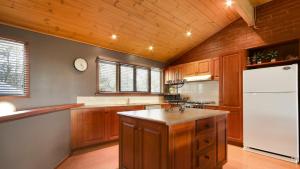 a kitchen with wooden cabinets and a white refrigerator at Lindsay Lachen in Mount Hotham