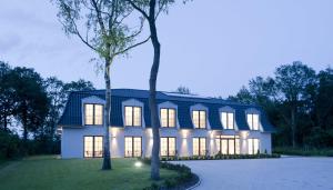 een wit huis met een gambrel dak bij Hotel Meiners in Kirchhatten