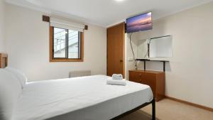 a bedroom with a white bed and a flat screen tv at Lawlers 17 in Mount Hotham +4 photos