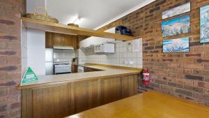 a kitchen with wooden cabinets and a brick wall at Lawlers 17 in Mount Hotham