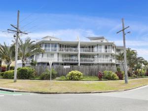 un grande edificio bianco con palme di fronte di Kawana Beachside Getaway 1 Bedroom Apartment a Buddina