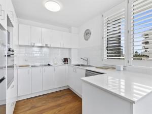 a white kitchen with white cabinets and a window at Kawana Beachside Getaway 1 Bedroom Apartment in Buddina