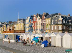 a group of people sitting on a beach with buildings at Le Chalet in Mers-les-Bains
