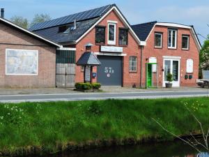 een rood bakstenen huis met een groene deur in een straat bij Spend the night in an old flour factory in Haulerwijk