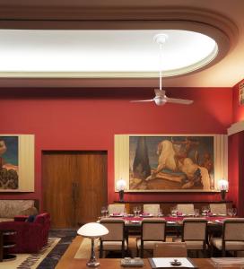 a dining room with tables and a painting on the wall at Umaid Bhawan Palace Jodhpur in Jodhpur