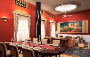 a dining room with red walls and a table and chairs at Umaid Bhawan Palace Jodhpur in Jodhpur