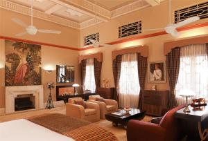 Umaid Bhawan Palace Jodhpur في جودبور: غرفة معيشة مع سرير ومدفأة