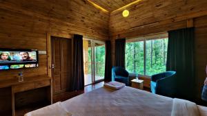 1 dormitorio con 1 cama y TV de pantalla plana en Coorg Bliss Estate Stay, en Madikeri