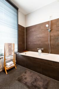een badkamer met een bad en een stoel bij Maison spacieuse unifamiliale. Gîte La Clochette in Bastenaken