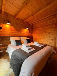 a large bed in a room with wooden walls at Chalet Le Montagnard SPA & SAUNA - Lits faits - Serviettes - Peignoirs - Ménage inclus in Rochesson