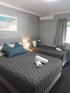 1 dormitorio con 2 camas y almohadas azules y blancas en Solomon Inn Motel Figtree, en Wollongong