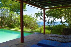 a swimming pool with a pergola next to a house at Villa Sarah Nafi, amazing ocean views in Temukus