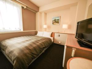 um quarto de hotel com uma cama e uma televisão de ecrã plano em Route Inn Grantia Fukuyama Spa Resort em Fukuyama