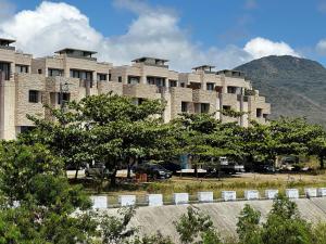 a large brick building with a mountain in the background at Kenting - Rest In Your Relax Time in Hengchun