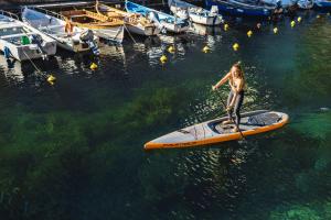 a woman standing on a paddle board in the water at BAIA in Brenzone sul Garda