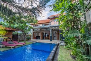 努沙杜瓦的住宿－Villa Padma by Best Deals Asia Hospitality，一座树木繁茂的房屋前的游泳池