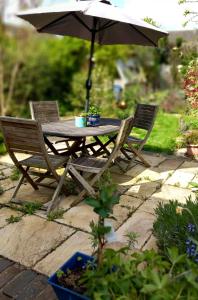 een houten tafel met 2 stoelen en een parasol bij Escape to the Country in wonderful Worcestershire in Ombersley