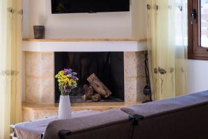 a living room with a fireplace with a vase of flowers at Villa Estrella with Heated pool in Aegina Town