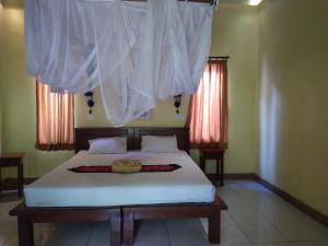 - une chambre avec un lit doté de draps et de rideaux blancs dans l'établissement Biorock Dive Support, à Pemuteran