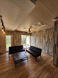 a living room with two black leather couches and a table at Cycle Guest House SHIOKAZE in Setoda