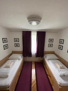 two beds in a small room with a window at Rosental Apartments Self Check-in in Ferlach