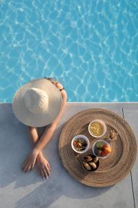 una donna con un cappello seduta accanto alla piscina di Irida Vacation suites a Kastraki