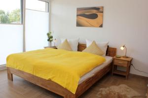 een slaapkamer met een bed met een gele deken bij Käptn Brass Villa 5 App 3 Strandrose in Dierhagen