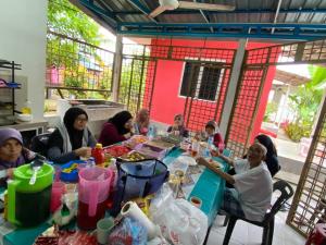 un grupo de personas sentadas en una mesa comiendo comida en CHALET MERAH MERIAM, YAN KEDAH, en Yan