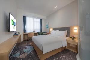een slaapkamer met een groot wit bed en een bureau bij Holiday Inn Express - Yantai YEDA, an IHG Hotel in Yantai