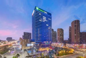 烟台烟台万行智选假日酒店的夜晚城市中的蓝色高楼