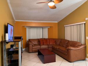a living room with a brown couch and a ceiling fan at Entire Single Family home 3 bed 2 bath in water front big cozy back yard view in Coconut Creek