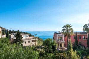 a house on a hill with the ocean in the background at Casa Bastione Taormina in Taormina