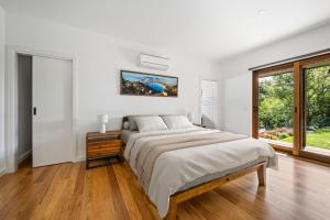ein weißes Schlafzimmer mit einem Bett und einem Fenster in der Unterkunft Edelweiss in Wandiligong