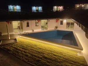 a house with a large swimming pool at night at D View Holiday Homes in Kudat