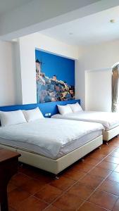 two beds in a bedroom with a painting on the wall at Fuyue Sea View B&B in Taitung City
