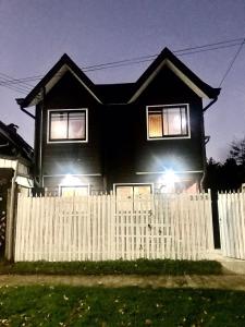 una casa negra con una valla blanca en Cabañas y Deptos Regional, en Valdivia