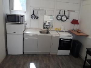 kuchnia z białymi szafkami, zlewem i kuchenką mikrofalową w obiekcie mini maison mini budget w mieście Soulac-sur-Mer