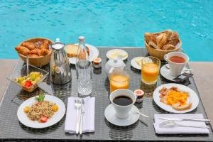 a table with breakfast foods and drinks and a pool at Hôtel L'Abbaye in Calvi