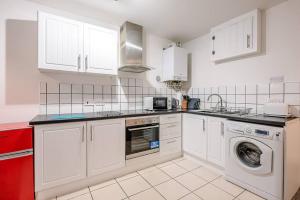 a kitchen with white cabinets and a washer and dryer at 1 Abbey Mews in Leiston