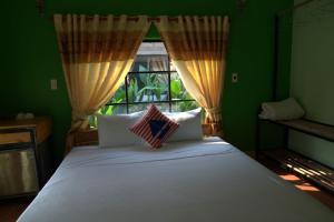 a bedroom with a large white bed with a window at Greenfield Ecostay in Phong Nha