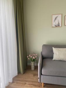 uma sala de estar com um sofá e um vaso de flores em Neringarent STUDIO-APARTAMENTAI em Juodkrantė