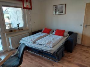 Bett mit zwei roten Kissen auf einem Zimmer in der Unterkunft Ferienwohnung Wiesenschneider´s in Freiensteinau