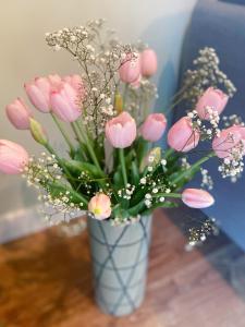 um vaso cheio de flores cor-de-rosa sobre uma mesa em Neringarent STUDIO-APARTAMENTAI em Juodkrantė