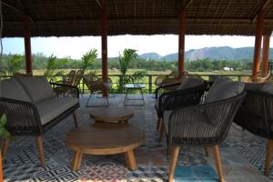 a patio with chairs and tables and a view of mountains at Greenfield Ecostay in Phong Nha