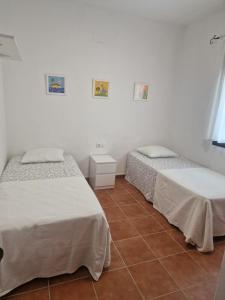 2 łóżka w pokoju z białymi ścianami i podłogą wyłożoną kafelkami w obiekcie Casa Alma w mieście Conil de la Frontera +37 zdjęć