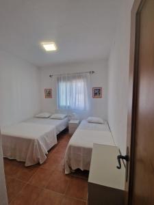 sypialnia z dwoma łóżkami, stołem i oknem w obiekcie Casa Alma w mieście Conil de la Frontera